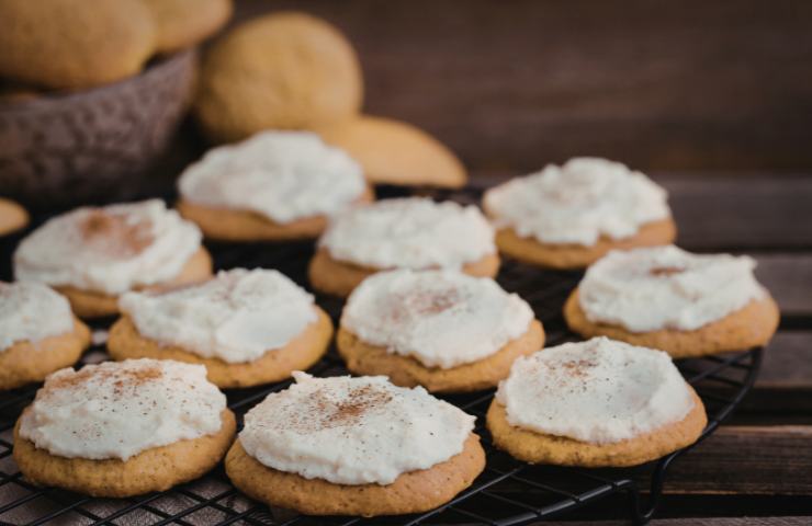 Biscotti alla zucca con frosting al formaggio spalmabile su una teglia