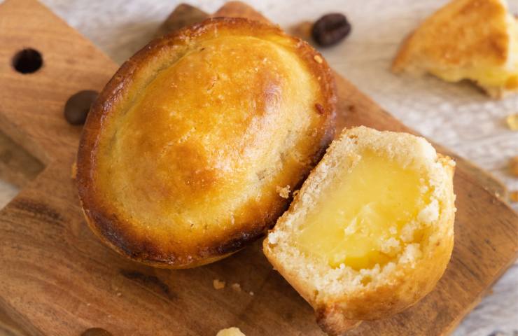 Un pasticciotto leccese intero e la metà di uno con crema su tagliere di legno