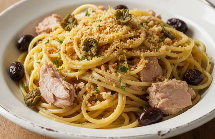 spaghetti con tonno, pangrattato aromatico, capperi fritti ed olive taggiasche in un piatto
