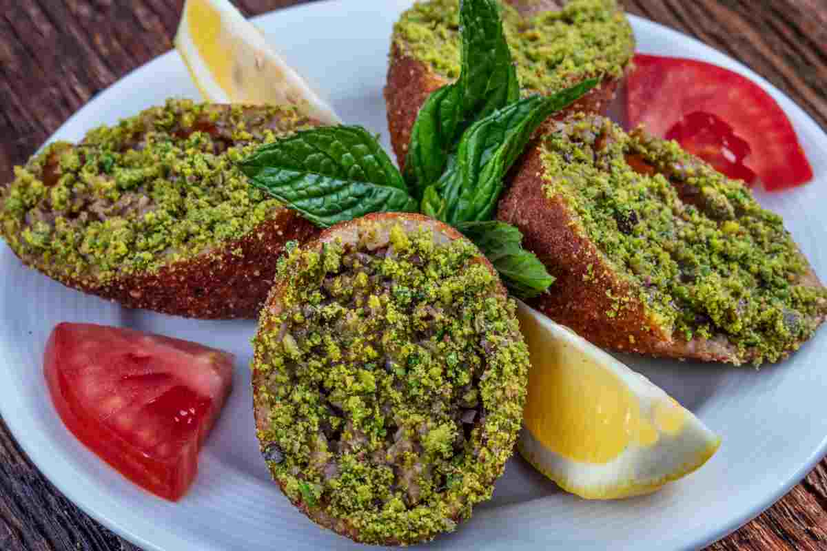 Kibbeh fritti con granella di pistacchio conditi in un piatto