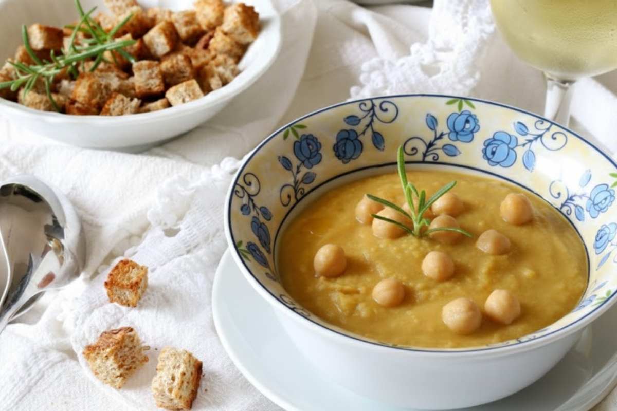 vellutata di ceci in un piatto con crostini sul tavolo