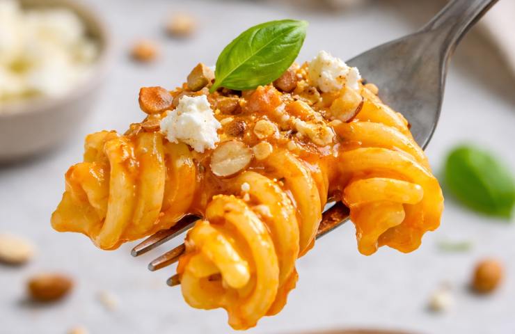 Fusilloni con crema di peperoni arrosto, feta e mandorle infilzati da una forchetta