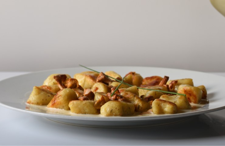 Gnocchi salsiccia funghi in un piatto bianco
