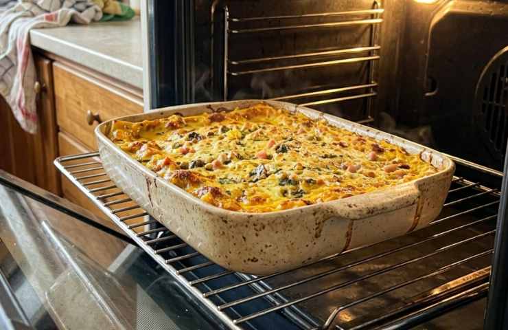 Lasagne gialle allo zafferano appena sfornate: teglia croccante estratta dal forno caldo in cucina domestica.