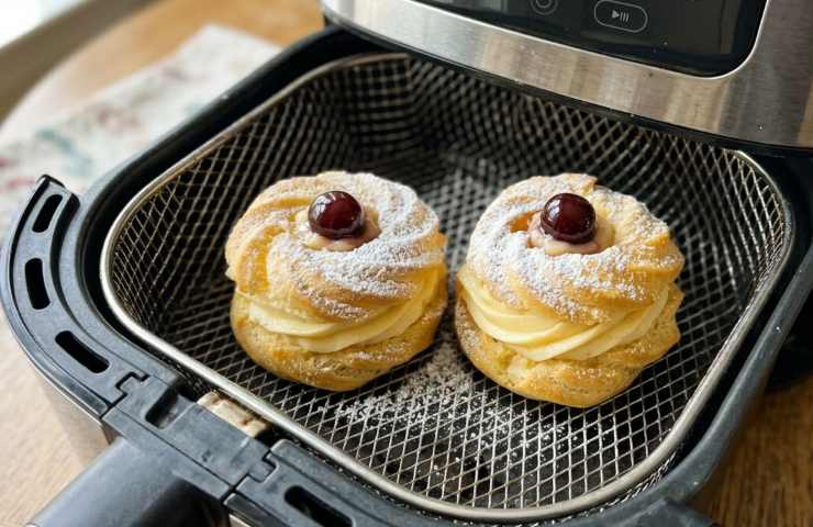 Cestello della friggitrice ad aria con zeppole di San Giuseppe appena cotte, versione leggera senza friggere.