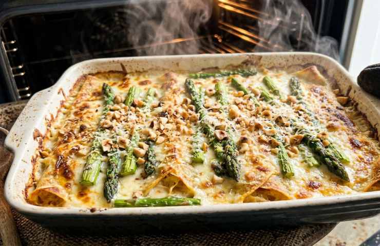 Crespelle agli asparagi e taleggio fumanti appena sfornate con granella di nocciole, primo piatto ricetta pranzo di Pasqua 2026.