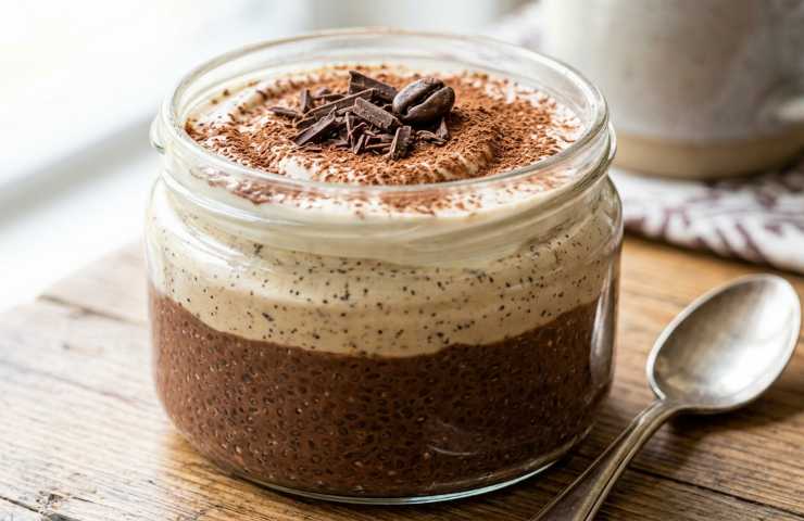 Mocaccino Chia Pudding a strati in un barattolo con cucchiaino accanto s tavolo.