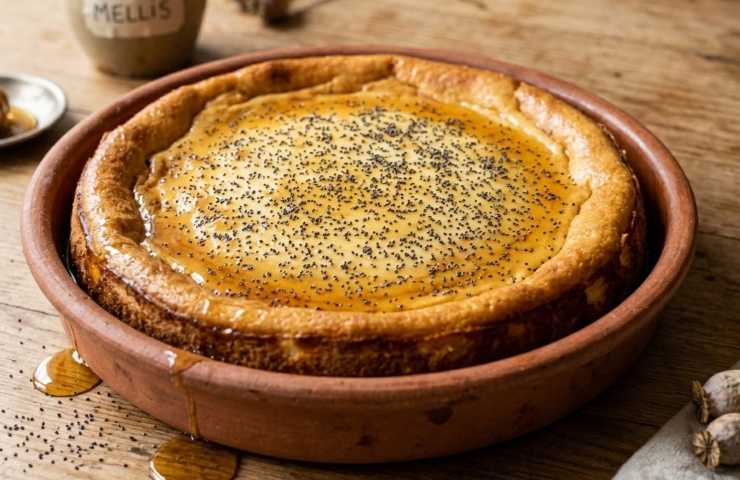 Torta intera Savillum, dolce romano al formaggio e miele, in teglia di terracotta su tavolo in legno.