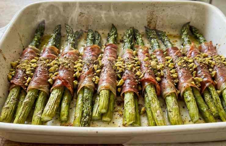Asparagi avvolti nel prosciutto appena cotti in una teglia forno.