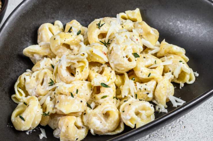 tortellini con panna in piatto nero