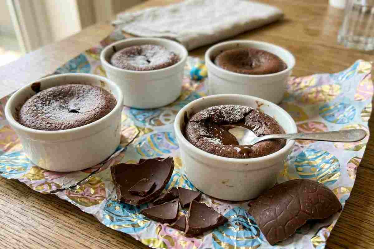 Tortini cuore morbido su carta colorata di uova di Pasqua aperte, con cioccolato rotto accanto.