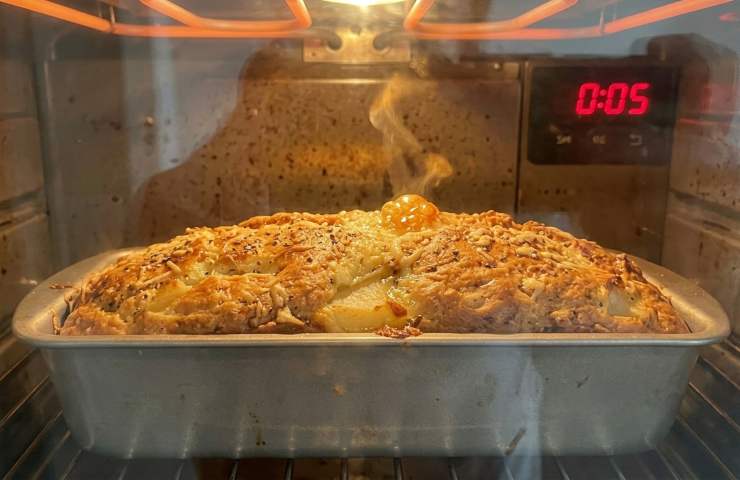 Cottura in forno del plumcake salato cacio e pepe con pere in stampo di metallo.