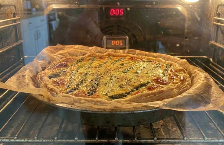 Torta salata di Pasquetta con asparagi e scamorza in cottura nel forno, dorata e filante.