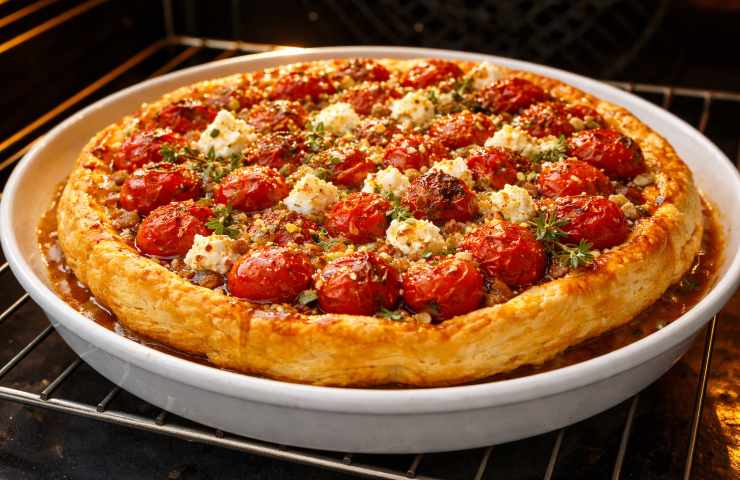 Tatin salata pomodorini e feta in forno negli ultimi secondi di cottura, sfoglia dorata e croccante con pomodori caramellati lucidi, foto realistica alta qualità.