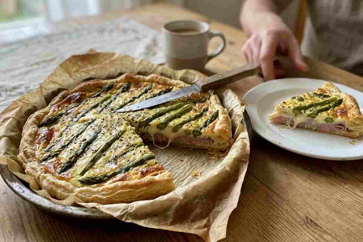 Torta salata di Pasquetta con asparagi e scamorza in cottura nel forno, dorata e filante.