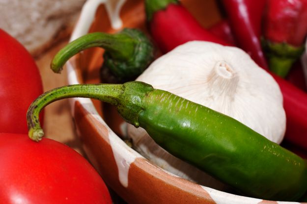 Green and red hot peppers in a bowl