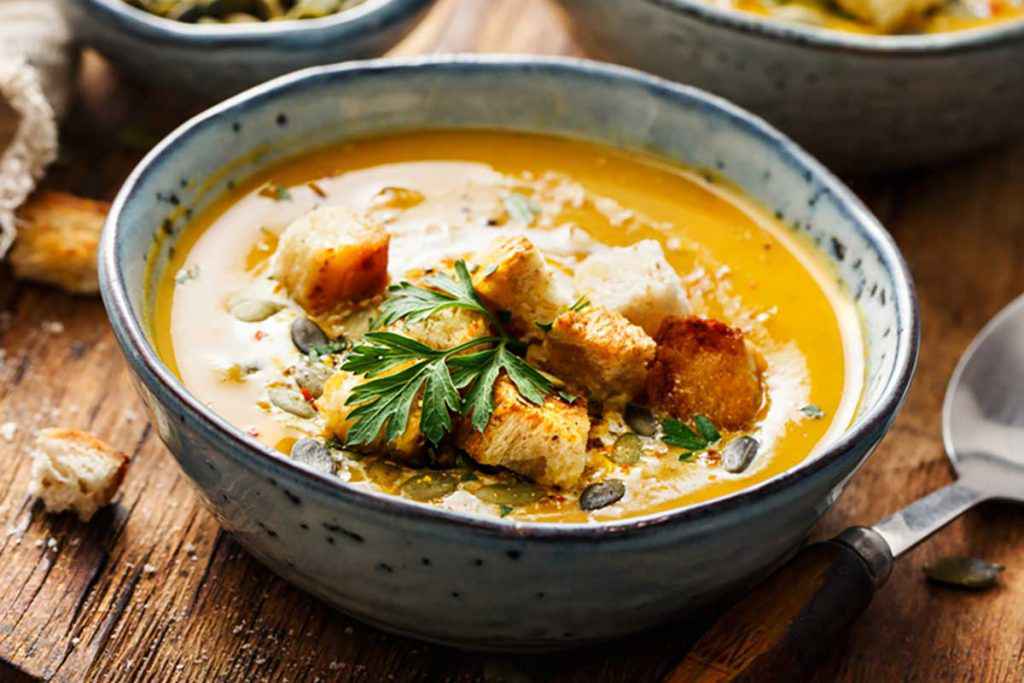 Scodella con zuppa arancione di carote e crostini di pane fritti
