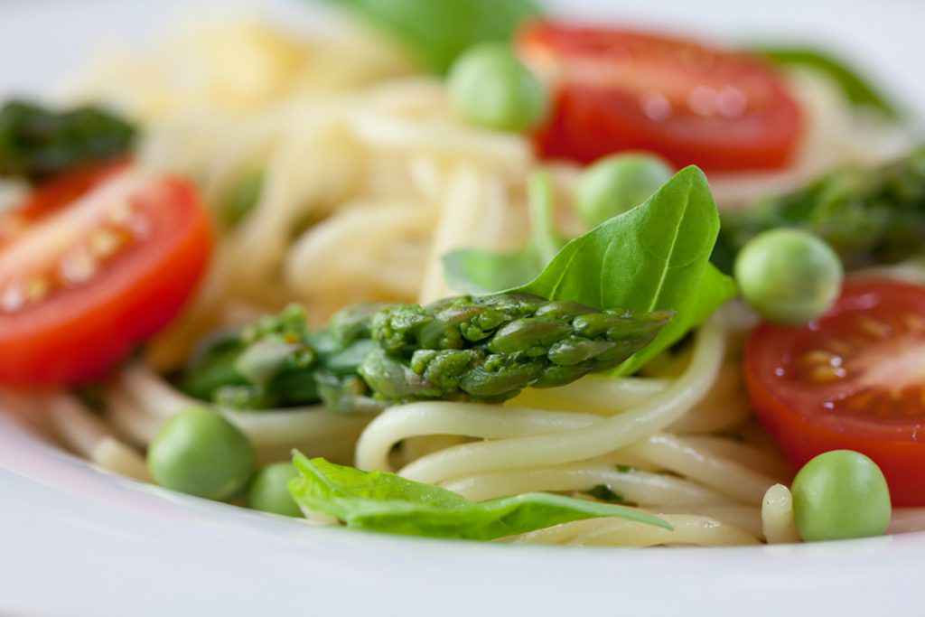 Pasta primavera con spaghetti, asparagi, piselli e pomodori