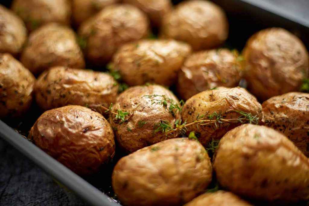 Teglia da forno piena di patate con buccia cotte